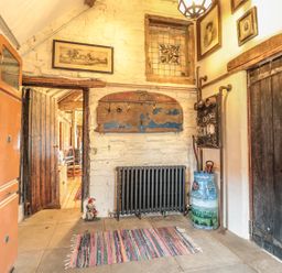 A rustic hallway with a striped rug wooden doors a radiator and vintage decorations at Jackdaw's Roost in Cheltenham