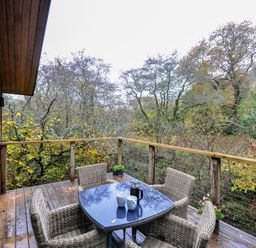 An outdoor area with a table and chairs overlooking trees at 2 Streamside Looe