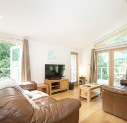 A living room with two brown leather sofas a wooden coffee table and a TV on a wooden stand at 7 Streamside in Lanreath