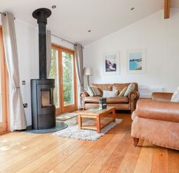 A living room with brown leather sofas a black wood stove and wooden coffee table at 6 Water's Edge in Lanreath