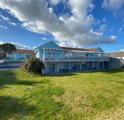 A two story house with a large lawn and covered swimming pool at The Sandcastle in Freshwater East