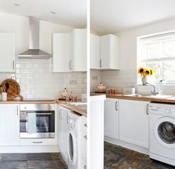 A kitchen with white cabinets wooden countertops a stainless steel oven washing machine and a window with sunflowers at Lilly Cottage in Whitecroft Royal Forest of Dean