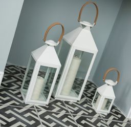 Three white lanterns with candles inside on a patterned floor at Teviot Cottage in Corbridge