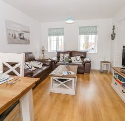 A living room with leather sofas a coffee table a television and dining table at Bayside Cottage The Bay near Filey