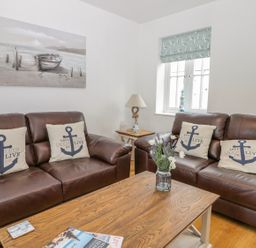 A living room with brown leather sofas and anchor themed cushions at Bayside Cottage The Bay near Filey
