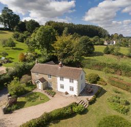 An aerial view of a countryside house with a gravel driveway garden and surrounding trees at Church View in Salisbury