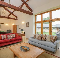 A living room with red and grey sofas and wooden beams at Lower Farm Barn Aston Near Bampton