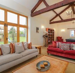 A living room with sofas cushions table bookshelf and a pool table at Lower Farm Barn in Aston Near Bampton
