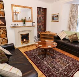 A living room with two leather sofas a round wooden coffee table a fireplace and a rug at Giddy Goose in Windermere