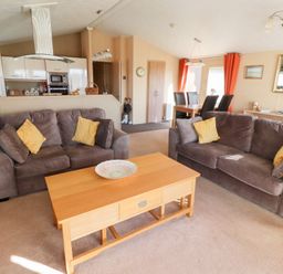 A living room with two brown sofas with yellow cushions and a wooden coffee table at Percy Wood Country Park in Swarland