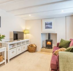A living room with a wood stove tv and a purple sofa at Beach Retreat in Instow