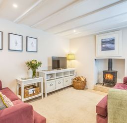 A living room with two sofas a wood-burning stove a television and framed pictures at Beach Retreat in Instow