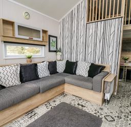 A living room with a corner sofa and patterned cushions at Meadow Retreat in Nantmel near Rhayader