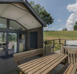 An outdoor area with a table, chairs and hot tub at Meadow Retreat in Nantmel near Rhayader
