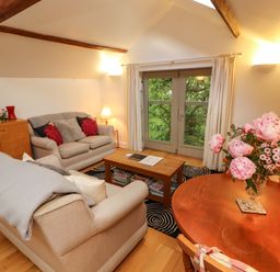 A living room with a sofa, coffee table, and dining table at Holemire Barn in Lorton