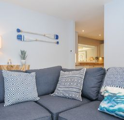 A living room with a blue sofa and patterned cushions with paddles on the wall at Coastal Haven in Crackington near Crackington Haven