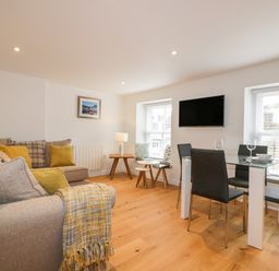 A living room with sofas and a dining table with chairs at The Crows Nest in Mevagissey