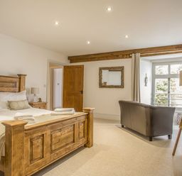 A bedroom with a wooden bed and bedside tables a leather chair and a window at The Penthouse Lynmouth Bay in Lynton