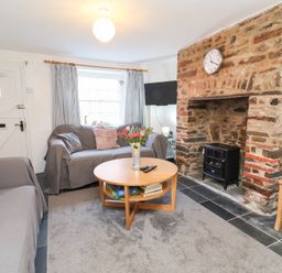 A living room with a sofa, coffee table, and fireplace at Willets Cottage in Appledore