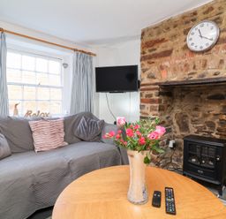 A living room with a sofa, television, and a coffee table at Willets Cottage in Appledore