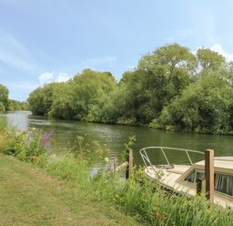 A river with trees on both sides and a boat moored by the riverbank at Thames Reach in Wallingford