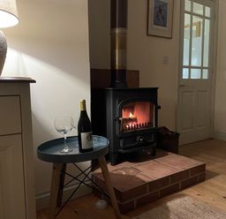 A living room with a stove, wine and glasses at Oreo's Cottage St Agnes