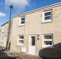 A stone cottage with white framed windows and a white door on a narrow street at Ammonite Cottage Fortuneswell Portland