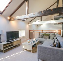 A living room with a gray sectional sofa coffee table tv and wooden beams at Barley Mews Brewers Quay Harbour