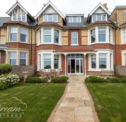 Back garden with a table set and chairs at a brick house with bay windows at Beach View Apartment 2 in Greenhill