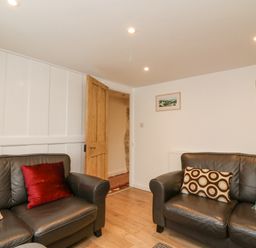 A sitting room with two leather sofas and patterned cushions at Bowman's Cottage in Wakeham Portland