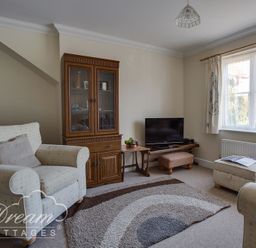 A living room with armchairs a wooden cabinet a television and a window at Bridge Apartment in Weymouth