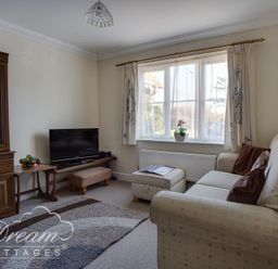 A living room with a sofa ottoman and television cabinet at Bridge Apartment in Weymouth