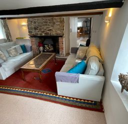 A living room with two sofas a coffee table a stone fireplace and a red rug at Culverwells in Axminster