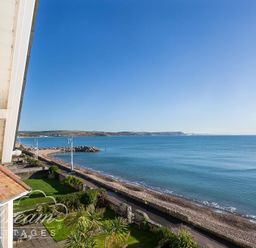 A view of a coastline with a beach road garden and blue sea at Dream View in Greenhill