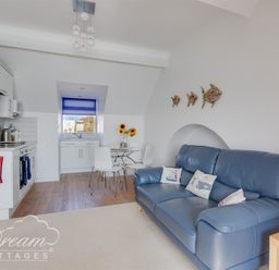 A kitchen and living area with a blue sofa and dining table with sunflowers at Dream View in Greenhill