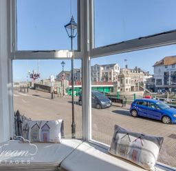 A bay window with cushions looking out onto a street with parked cars and buildings at Harbour Edge Brewers Quay Harbour