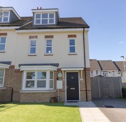 A semi detached house with black front door and multiple windows with a green lawn and paved driveway at The Ferns in Weymouth