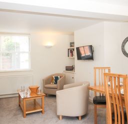 A living room with chairs a dining table and a wall mounted tv at Firkin Cottage Brewers Quay Harbour
