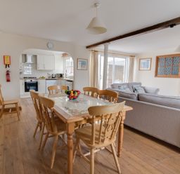 A dining area with a wooden table and chairs next to a kitchen and a living room with sofas at Georges House in Brewers Quay Harbour