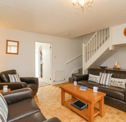 A living room with leather sofas wooden coffee table and staircase at Home Waters in Wyke Regis