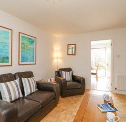 A living room with dark leather sofas striped pillows wooden table and paintings at Home Waters in Wyke Regis