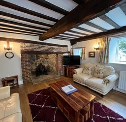 A living room with a fireplace and sofa at Ivy Cottage in West Lulworth