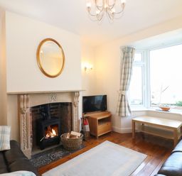 A living room with a fireplace a round mirror above and two leather sofas at Langham Cottage in Portland