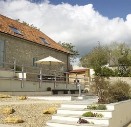 An outdoor patio area with a stone building roof and stairs with plants at Leys At Valley View Farm in Uplyme