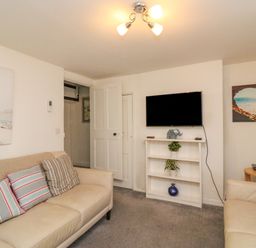 A living room with two beige sofas and a wall-mounted TV at Lobster Cottage Brewers Quay Harbour