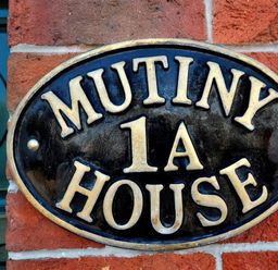 A plaque displaying 'Mutiny House 1A' on a brick wall at Mutiny House in Brewers Quay Harbour