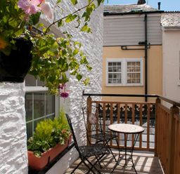 A small balcony with two chairs a round table and plants on the railing at Courtyard House Dartmouth