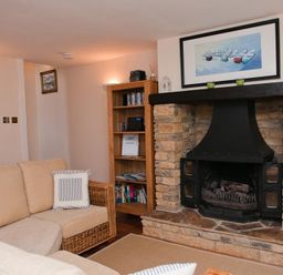 A living room with a beige sofa a stone fireplace a wooden bookshelf and a framed picture above the fireplace at Courtyard House Dartmouth