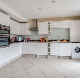 A kitchen with white cabinets appliances and a tiled floor at New Boathouse in Weymouth