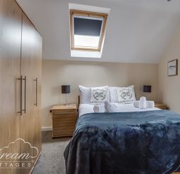 A bedroom with a double bed bedside tables lamps a wardrobe and a skylight window at Old Boathouse Weymouth